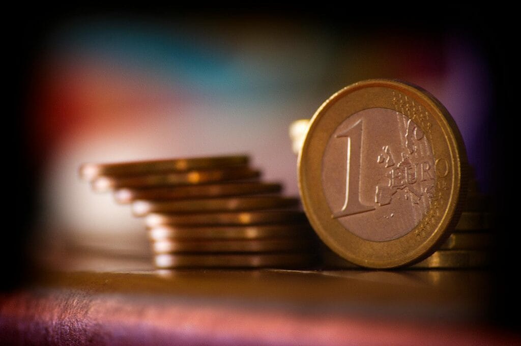 A close-up shot of stacked euro coins with a blurred colorful background, representing financial concepts.