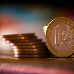 A close-up shot of stacked euro coins with a blurred colorful background, representing financial concepts.